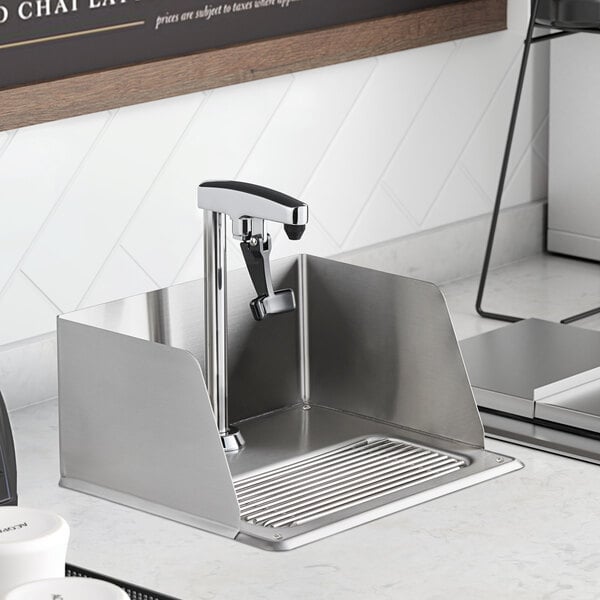 A Regency glass filler station with splash guard and glass filler in a stainless steel sink on a counter in a professional kitchen.