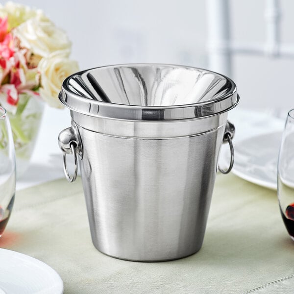 An Acopa stainless steel wine tasting spittoon on a table.