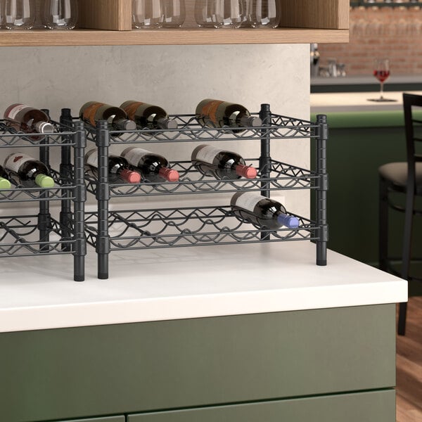 A black wire wine rack holding bottles of wine on a counter.