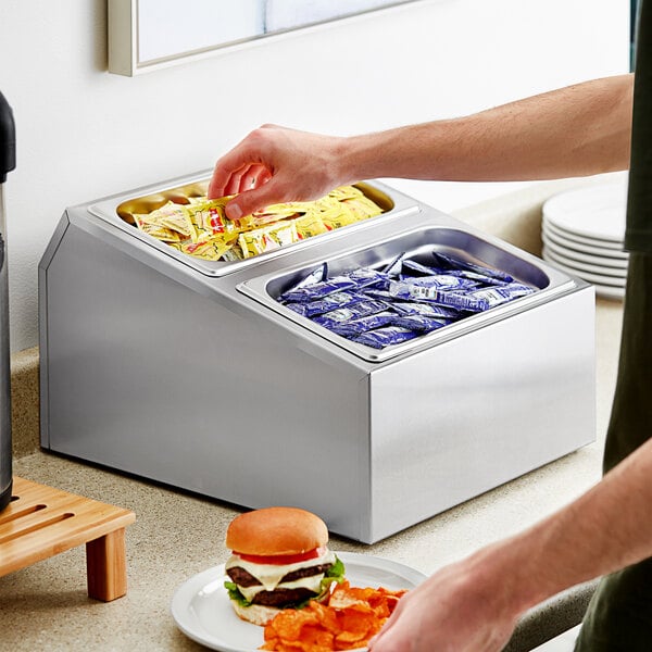 A person taking a food container from a stainless steel organizer holding two food containers.