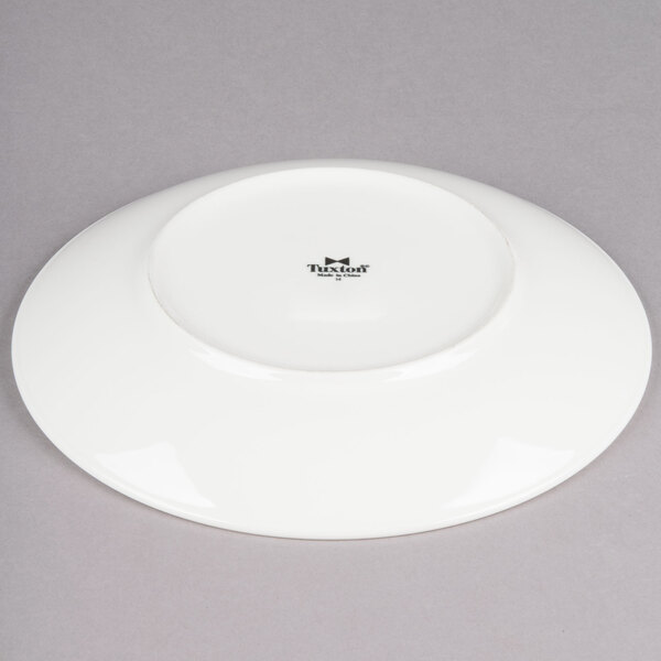 A Tuxton Venice ivory china plate with an eggshell finish and a black rim.