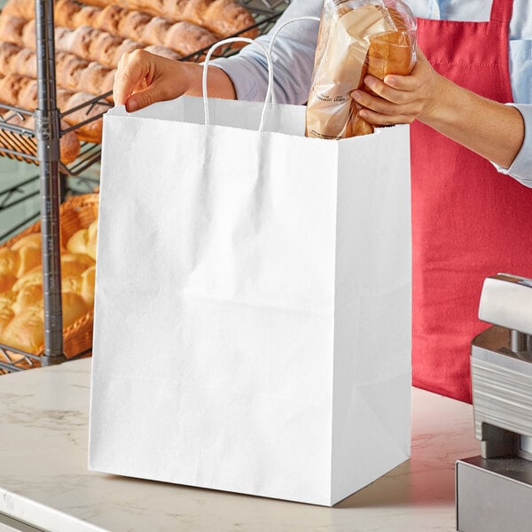 A woman holding a Duro white paper shopping bag filled with bread.