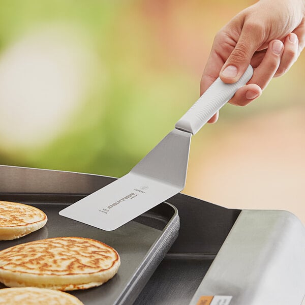 A person using a Dexter-Russell solid turner to flip a pancake.