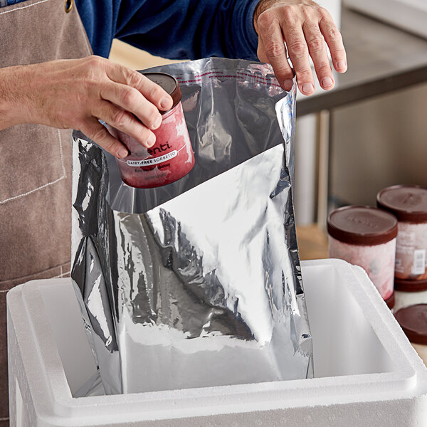 A hand putting a can of yogurt into a silver Metallized Thermalast liner bag.