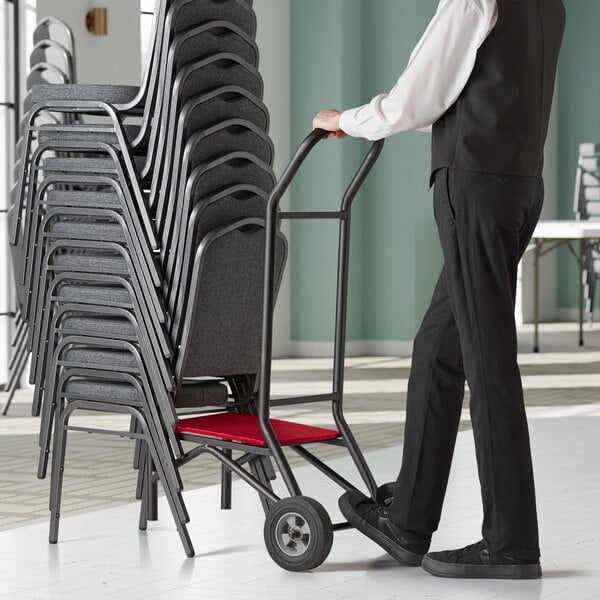 employee moving a stack of chairs with a chair dolly