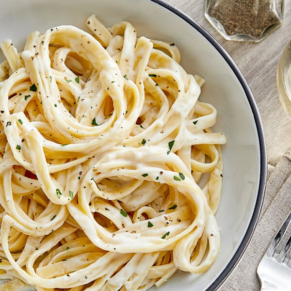A plate of pasta with Alfredo sauce and a fork.