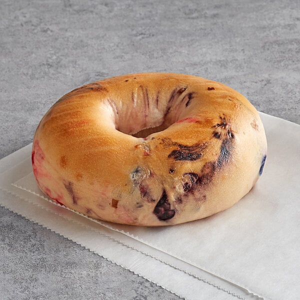 A New York style bagel with blueberry filling on a napkin.