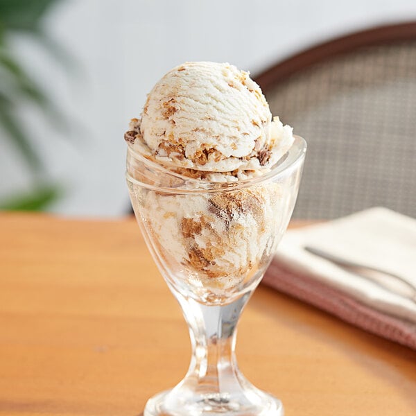 A glass cup with a scoop of ice cream topped with chopped REESE'S Peanut Butter Cup.