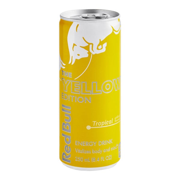 A close up of a yellow Red Bull Tropical energy drink can.