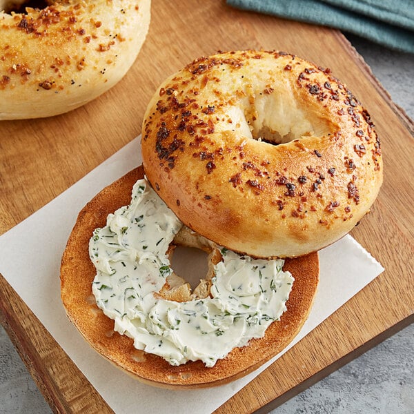 A close up of a New York style garlic bagel with cream cheese on top.