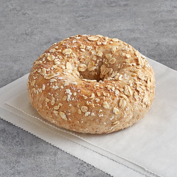 An Original Bagel wheat bran bagel with oats on a napkin.