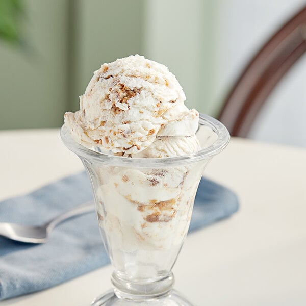 A glass cup with a scoop of ice cream topped with chopped REESE'S Peanut Butter Cup.