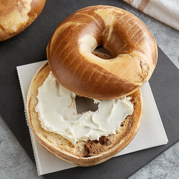 A marble bagel with cream cheese on top of it.