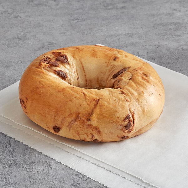 An Original Bagel New York style bagel with chocolate chips on top on a napkin.