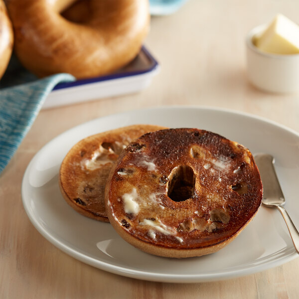 A cinnamon raisin bagel with butter on a plate.