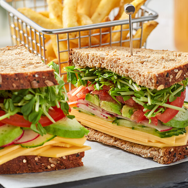 A sandwich with lettuce, tomatoes, and Violife vegan cheddar cheese slices on a white surface.