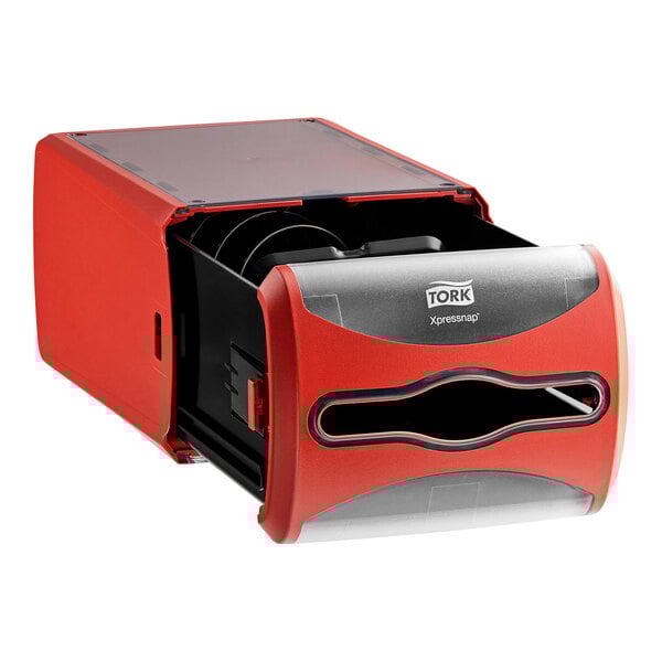 A red and black Tork countertop napkin dispenser with a black lid.
