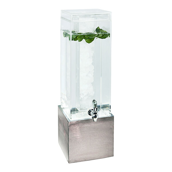 A Cal-Mil clear plastic beverage dispenser with a plant in it on a gray and white base.