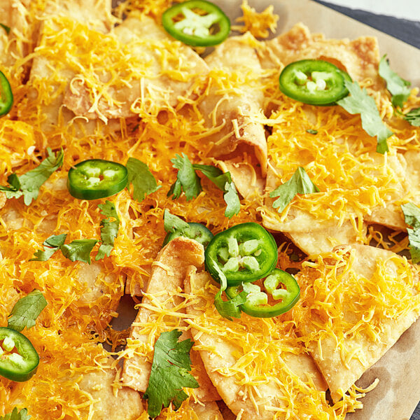 A plate of nachos with Violife Just Like Cheddar vegan cheese and jalapenos.
