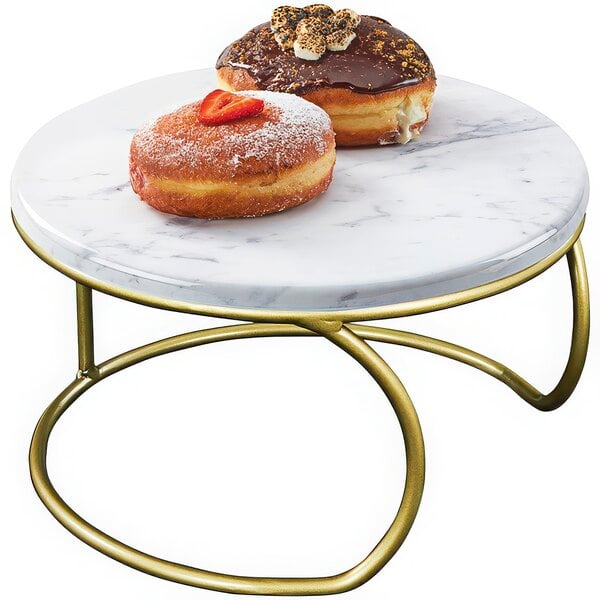 A Cal-Mil white marble display riser with gold accents holding a donut with a strawberry on top.