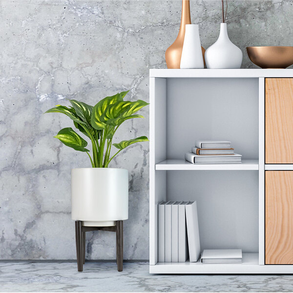 A white ceramic plant stand with a plant in it.
