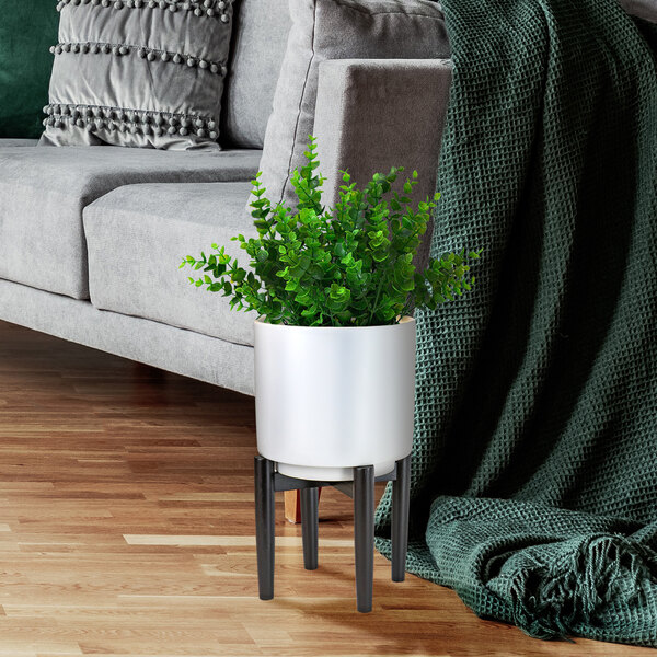 A white ceramic plant stand with a plant in a white pot.