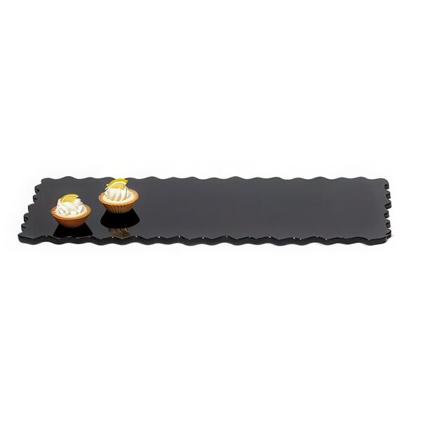 A black rectangular tray with two small cupcakes on it.