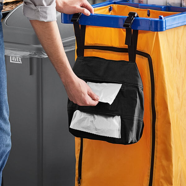 A man putting a black Lavex double pocket trash bag in a trash can.