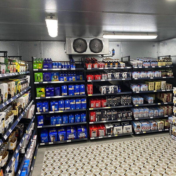A store shelf with B-O-F Corporation VersaRack beer shelving holding bottles of alcohol.