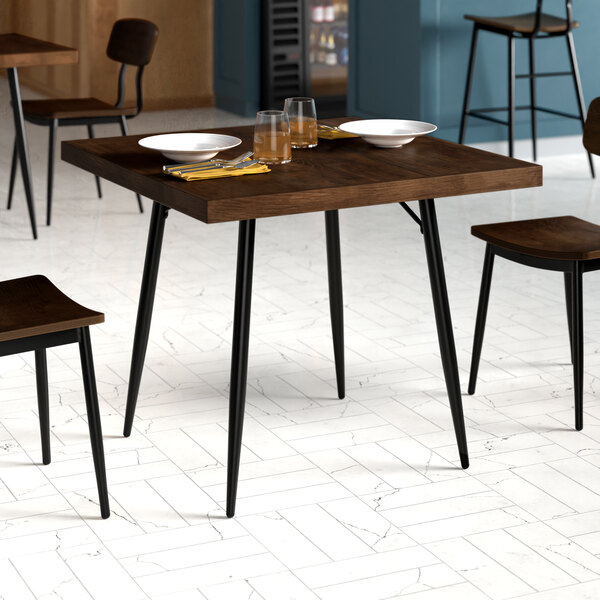 A Lancaster Table & Seating butcher block table with plates and glasses on it, surrounded by chairs.