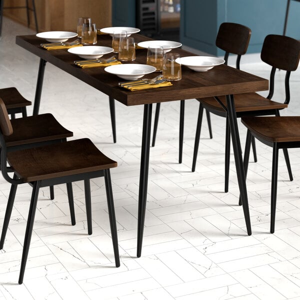 A Lancaster Table & Seating butcher block table with espresso finish and chairs with black frames set with plates and forks.