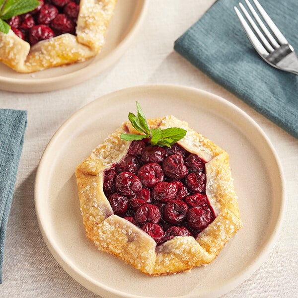 A close-up of a plate with a cherry pie and a fork.