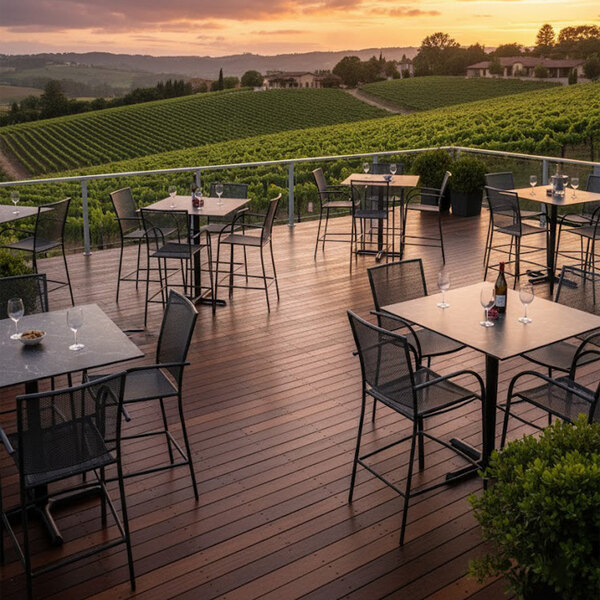 A black faux marble bar height table with a cross base, set on an outdoor patio overlooking a vineyard.