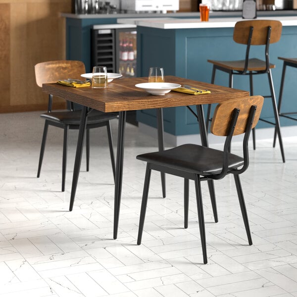 A Lancaster Table & Seating butcher block table with plates and chairs in a kitchen.