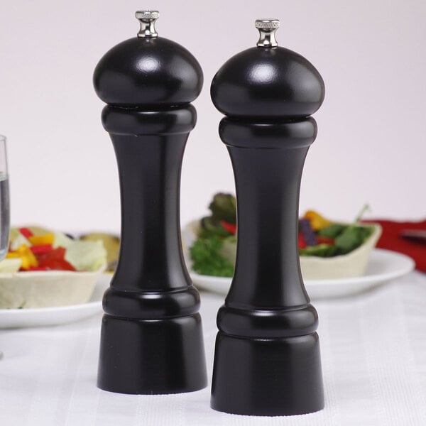 Two black Chef Specialties Windsor ebony finish pepper mills on a table.