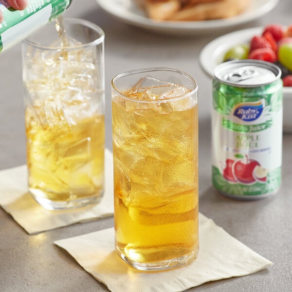 A hand pouring Ruby Kist apple juice from a can into a glass with ice.