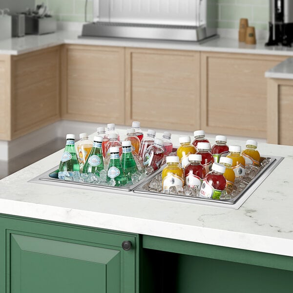 A school kitchen counter with a ServIt drop-in food well filled with ice and bottles of soda.