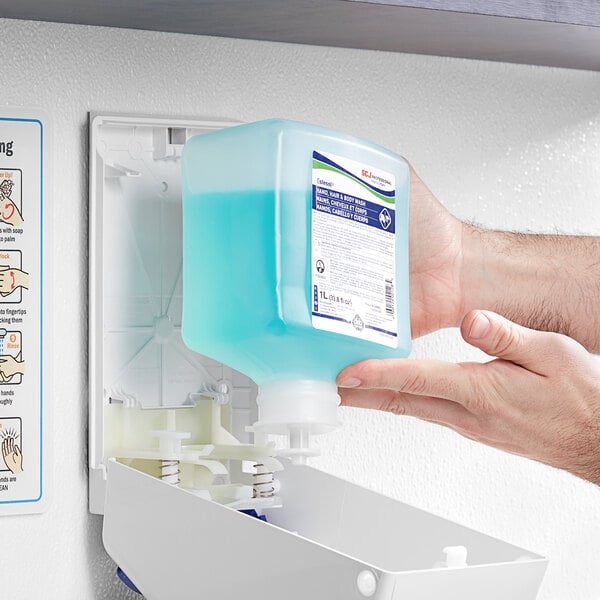 A person holding a blue bottle of SC Johnson Professional Estesol hand, hair, and body wash.