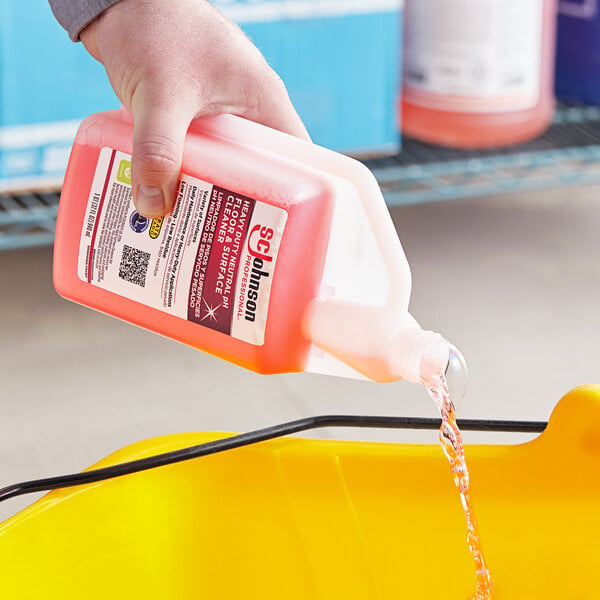 A hand pouring SC Johnson Professional Heavy-Duty Neutral Floor Cleaner into a yellow bucket.