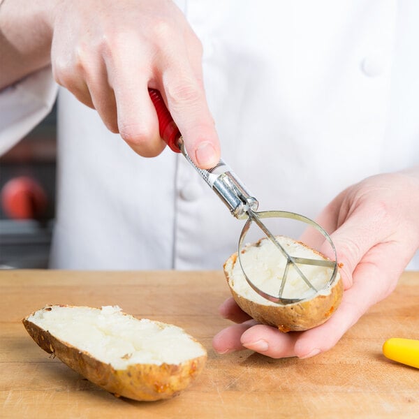 A person using a Vollrath Tater King Scooper to cut a potato.