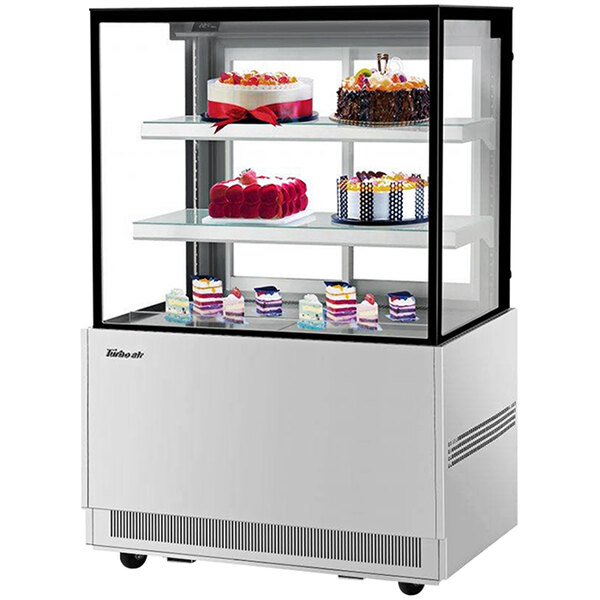 A Turbo Air refrigerated bakery display case with cakes and desserts inside.