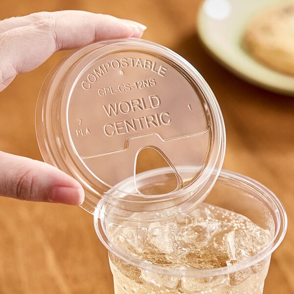 A hand using a World Centric compostable plastic lid on a cup of ice.