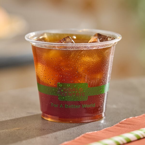 A clear compostable plastic cup filled with iced tea or a similar cold beverage.