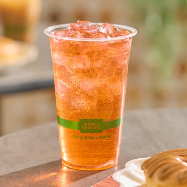 A clear compostable plastic cup filled with iced tea or a similar cold beverage.