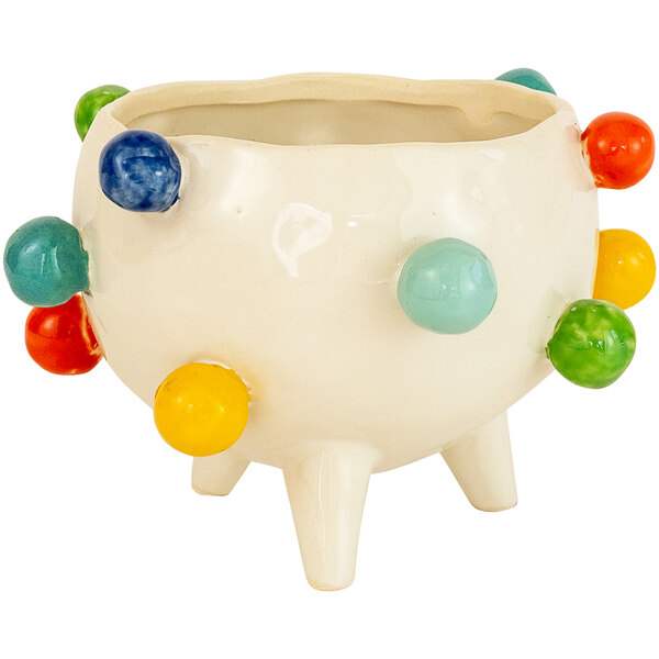 A white ceramic pot with multicolored balls on it.