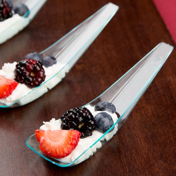 A group of Fineline green plastic spoons with fruit and cream on them.