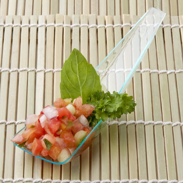 A Fineline Tiny Tensils green plastic spoon with salsa on a table.