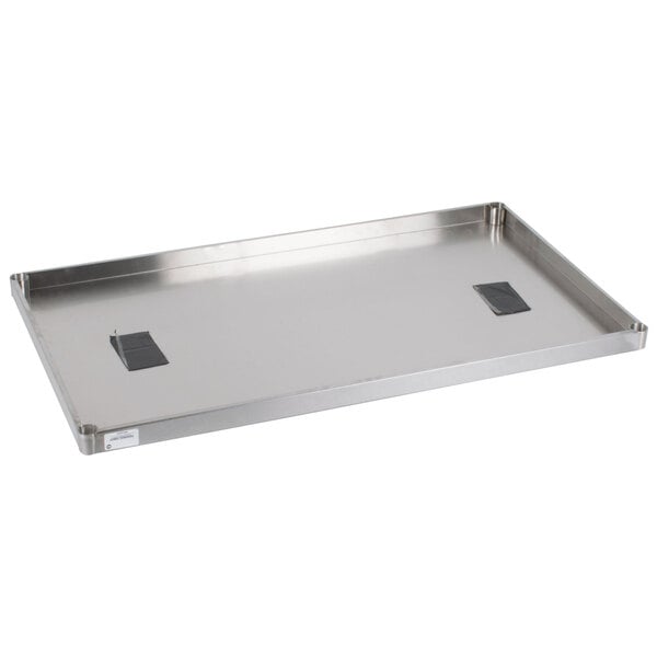 An Advance Tabco solid stainless steel shelf on a counter with two black objects on top.