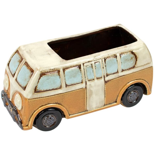 A yellow ceramic van shaped planter on a white base.