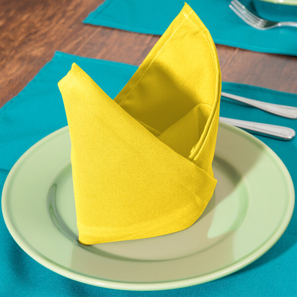 A folded yellow Intedge cloth napkin on a plate.
